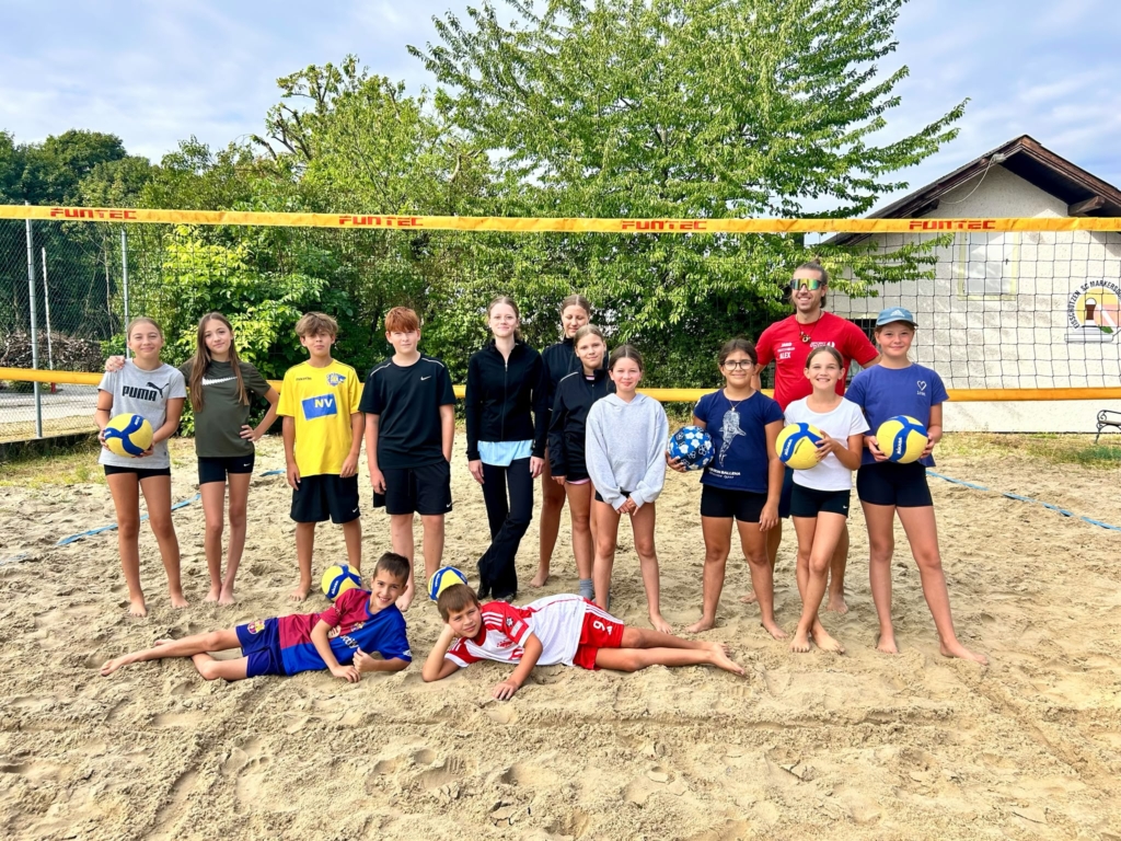 Kinder mit Trainer am Beachvolleyballplatz