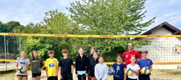Kinder mit Trainer am Beachvolleyballplatz